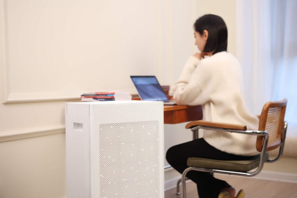 a woman sitting next to sa600 air purifier