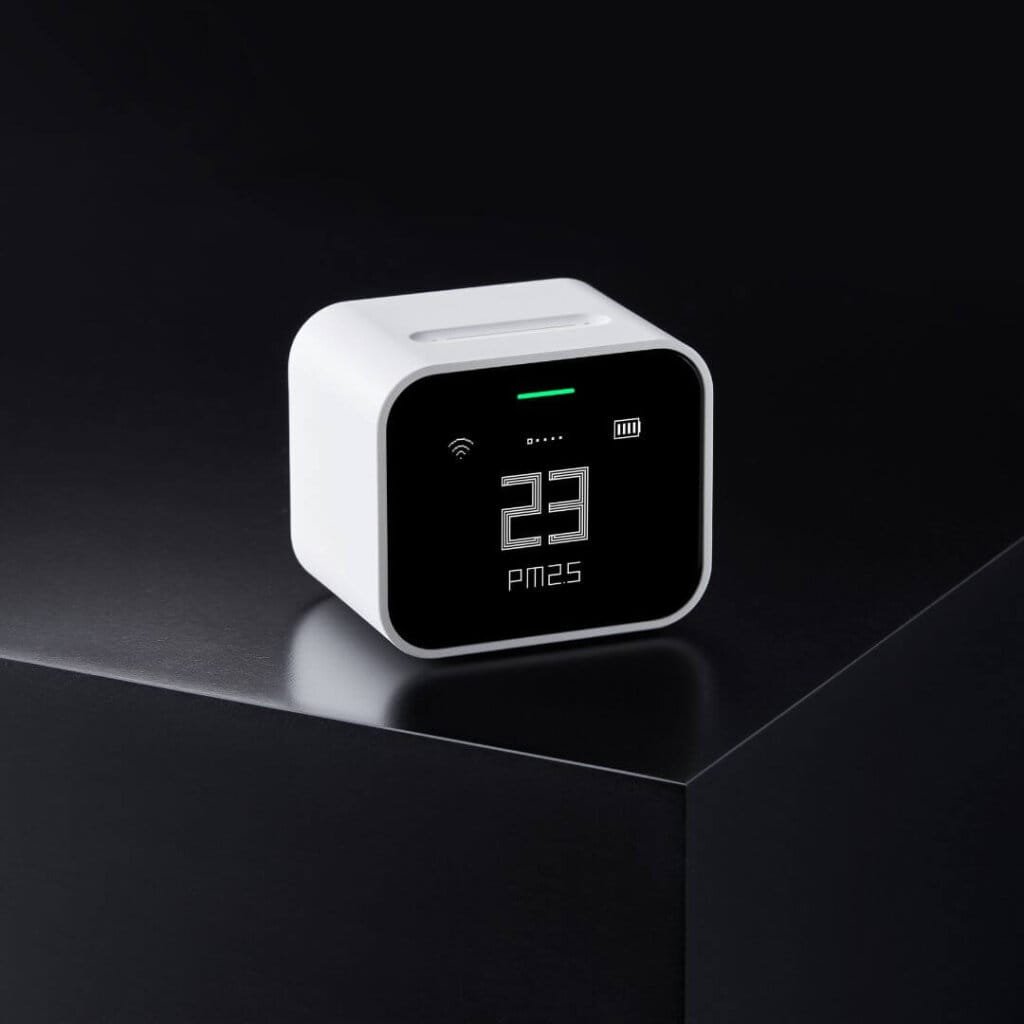 qingping lite air quality monitor on a black table on black background