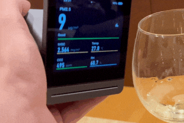 a gif animation of an air quality monitor next to a white wine