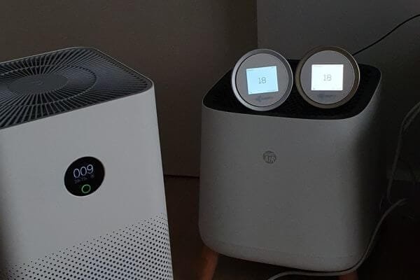 two external air quality monitors next to a built-in sensor of a xiaomi air purifier displaying different air quality readings.