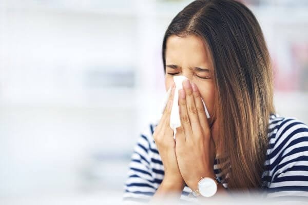 a woman sneezing into a tissue