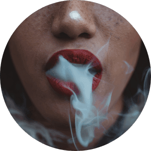 a closeup of a woman's mouth filled with cigarette smoke.