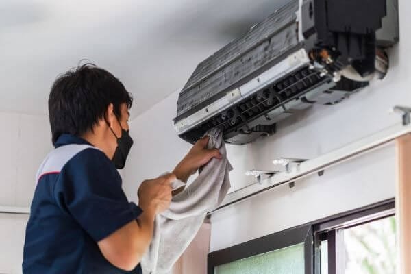 a technician cleaning and repairing an air conditioner