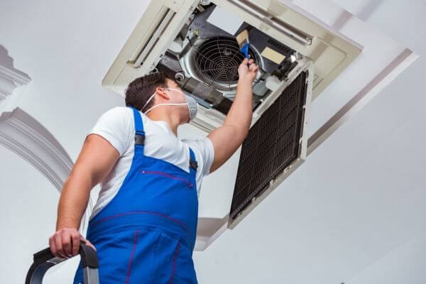 an hvac technician inserting hepa filter inlets into a central air conditioner system