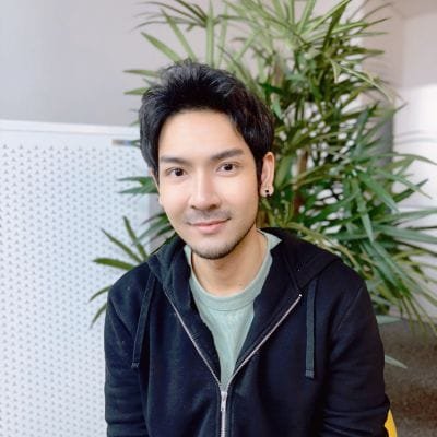 เพชรนั่งอยู่หน้ามเครื่องฟอกอากาศและดอกไม้เป็นฉากหลัง